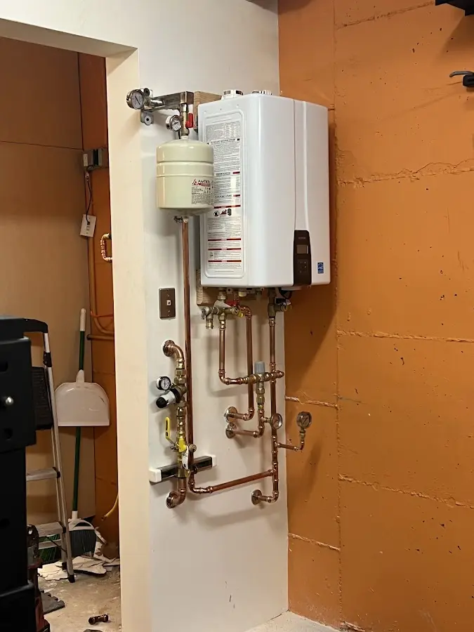 Plumbing technician inspecting water heater connections in Battle Creek